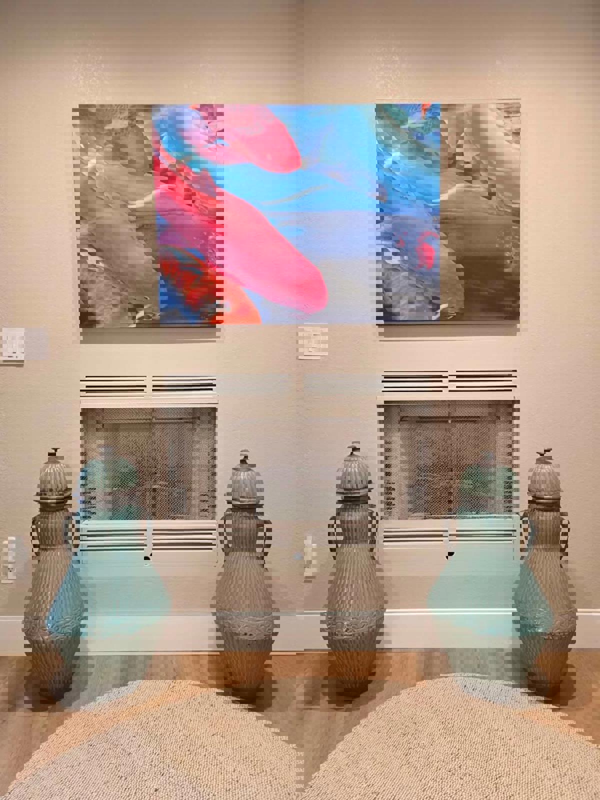 Two large turquoise vases in front of a fireplace with a colorful fish painting above.