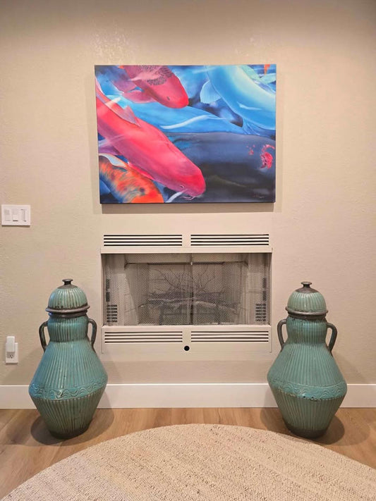 Two large turquoise vases in front of a fireplace with a colorful fish painting above.