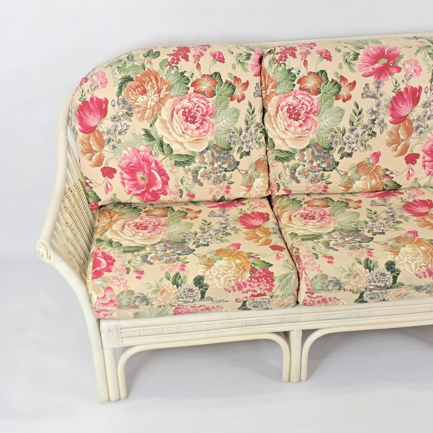Whitewashed Rattan Sofa with Floral Cushions