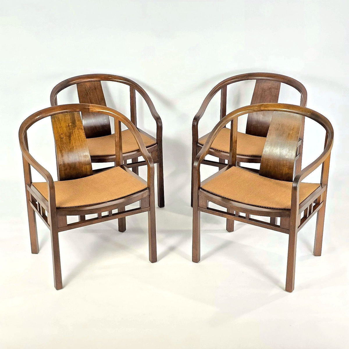 Four wooden armchairs with curved backs and tan woven seats, arranged in two pairs on a plain white studio background.